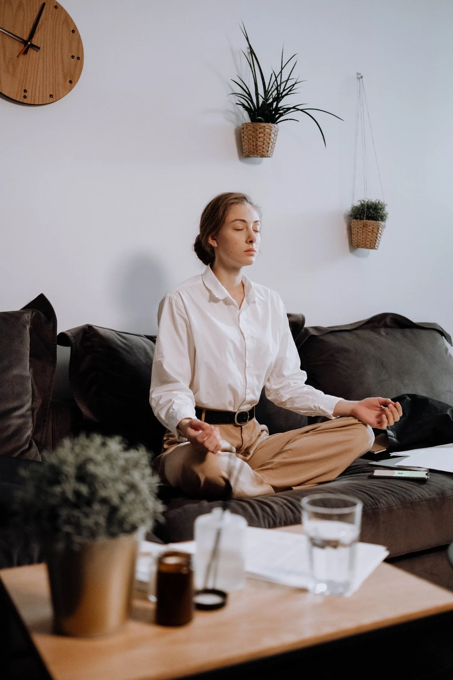 Woman meditating cross-legged on a sofa in a calm living room